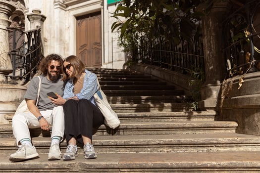 Beautiful hipster couple in love sitting stairs on old city street and looking on phone photo