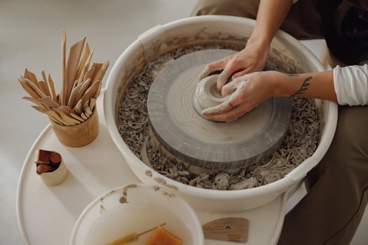Close up of hands of professional potter molding pot shape on pottery wheel. Ceramics art concept photo