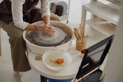 Close up of hands of professional potter molding pot shape on pottery wheel. Ceramics art concept photo