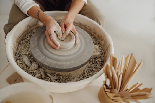 Close up of hands of professional potter molding pot shape on pottery wheel. Ceramics art concept photo