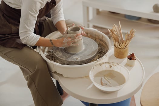 Close up of hands of professional potter molding pot shape on pottery wheel. Ceramics art concept photo