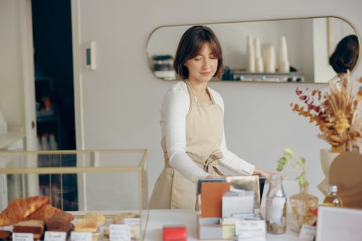 Female barista in apron standing at the counter in coffee shop and takes orders from client photo