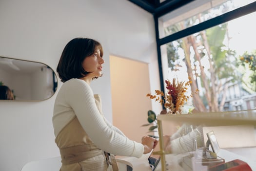 Female barista in arpon standing at the counter in coffee shop and takes orders from client photo