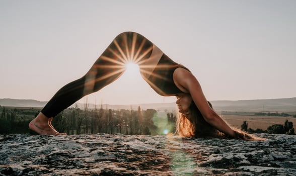 Fitness woman. Well looking middle aged woman with long hair, fitness instructor in leggings and tops doing stretching and pilates on the rock near forest. Female fitness yoga routine concept. photo