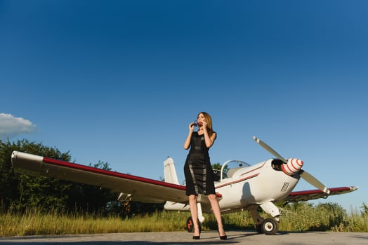 Full length of rich woman in elegant dress standing against limousine and private photo