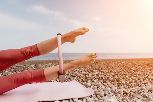 Woman sea pilates. Sporty happy middle aged woman practicing fitness on beach near sea, smiling active female training with ring on yoga mat outside, enjoying healthy lifestyle, harmony and meditation photo