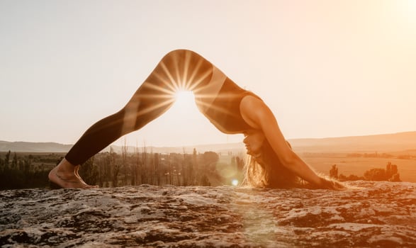Fitness woman. Happy middle-aged fitness woman doing stretching and pilates on a rock near forest at sunset. Female fitness yoga routine. Healthy lifestyle with focus on well-being and relaxation. photo