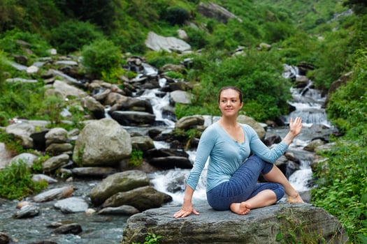 Woman doing Ardha matsyendrasana asana outdoors photo