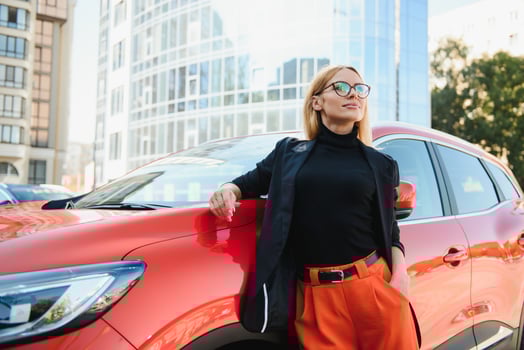 Yong pretty woman standing near a big all terrain car outdoors. Driver girl in casual clothes outside her vehicle. photo
