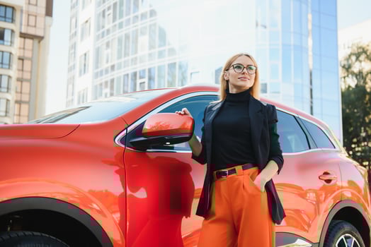 Yong pretty woman standing near a big all terrain car outdoors. Driver girl in casual clothes outside her vehicle. photo