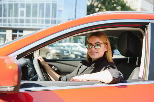 successful businesswoman driving car through modern urban city with reflections of buildings photo
