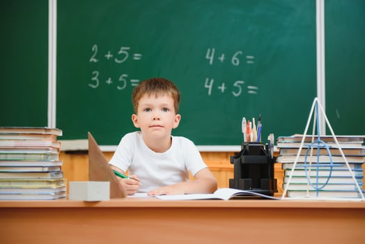 Back to school. Funny schoolboy sitting at a table with books in a school classroom. photo