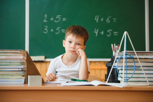 Back to school. Funny schoolboy sitting at a table with books in a school classroom. photo