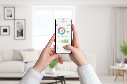 Woman holds smartphone with electricity usage app, monitoring and analyzing consumption for smart home. Living room background. Concept of energy efficiency photo