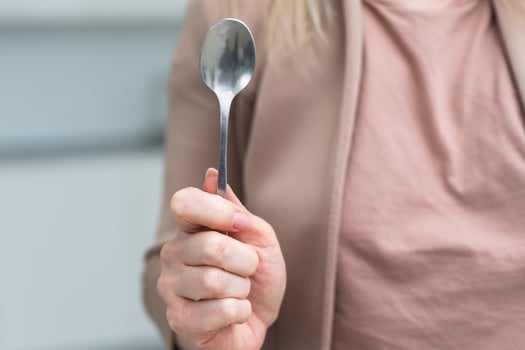 Metallic empty eating spoon in a human right hand with clipping path isolated on white photo