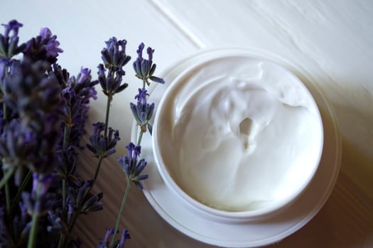 Lavender flowers, candles and cream on a white wooden background. Beauty care. Top view. photo