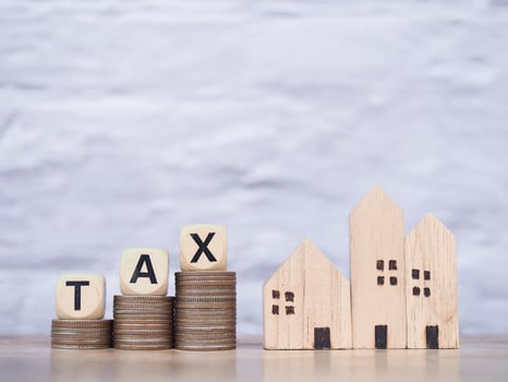 Miniature house and Wooden blocks with the word TAX on stack of coins. The concept of payment tax for house, Property investment, House mortgage, Real estate photo