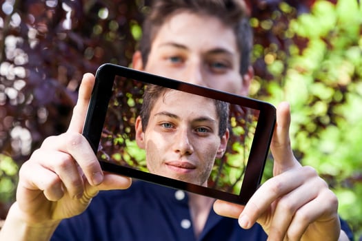young millennial man taking a selfie with smart phone outdoors photo