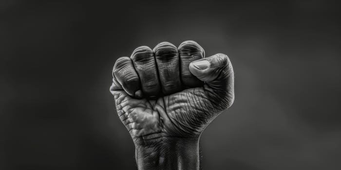 AI generated This black and white photo captures a person raising their fist in a powerful gesture. The image conveys strength, determination, and defiance