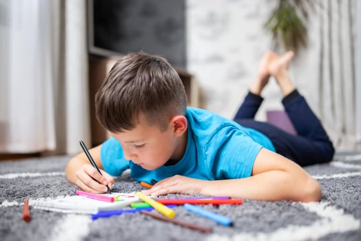 A boy lies on the floor and draws a notebook with colorful markers photo