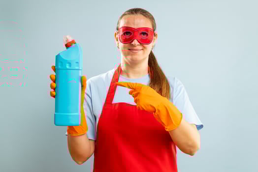 Woman in red mask, rubber gloves and apron holding cleaning agent bottle photo