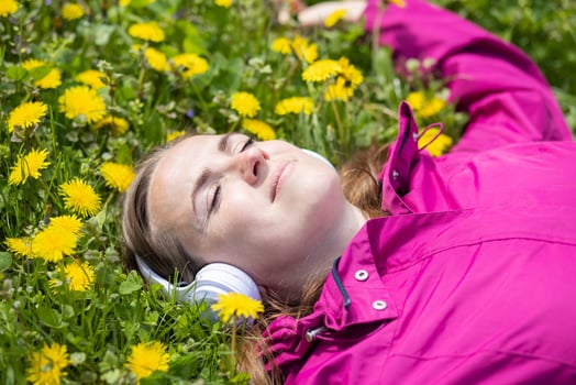 Beautiful young woman in headphones listens to music lying on the grass photo