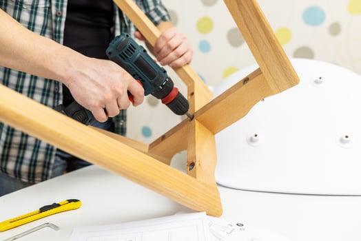 Assemble furniture. Man assembling chair. Furniture assembler with drill photo