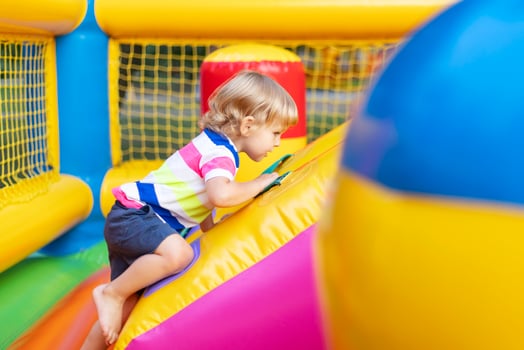 Happy kid having fun on colorful inflatable attraction playground photo