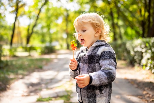 Funny child with candy lollipop, little boy eating big sugar lollipop outdoors photo