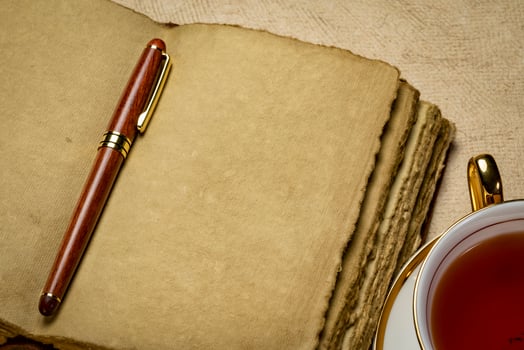 blank retro leather-bound journal with decked edge handmade paper pages with a stylish pen and a cup of tea, journaling concept photo