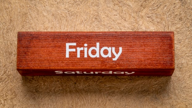 Friday and Saturday text on wooden block against handmade bark paper in earth tones, calendar concept photo