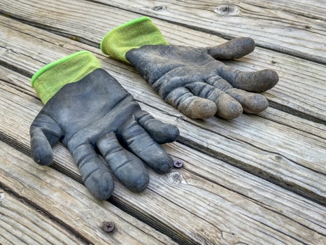 a pair of well used, dirty bamboo garden gloves on a wooden rustic deck photo