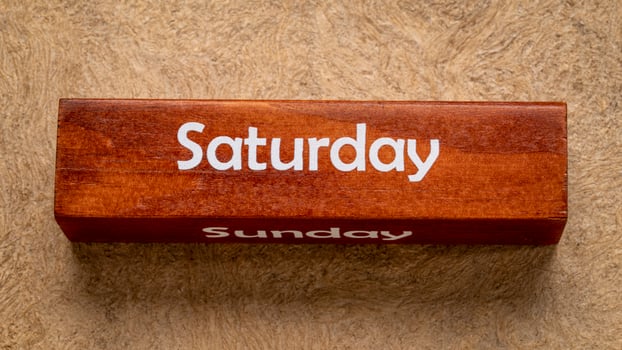 Saturday and Sunday text on wooden block against handmade bark paper in earth tones, calendar concept photo