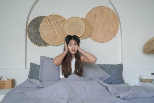 Asian woman waking up in the morning feeling stressed and getting headache after deep sleep, still feeling tired and sleepy stay sitting on bed in the bedroom photo