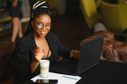 Satisfied african girl using laptop at cafe, working online, copy space photo
