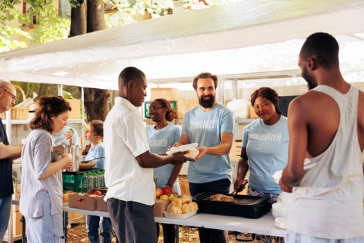 Assisting the needy, compassionate volunteers distribute essential items at a homeless center. Non-porift hunger relief team provide free food, support, and donations to the poor and less privileged. photo