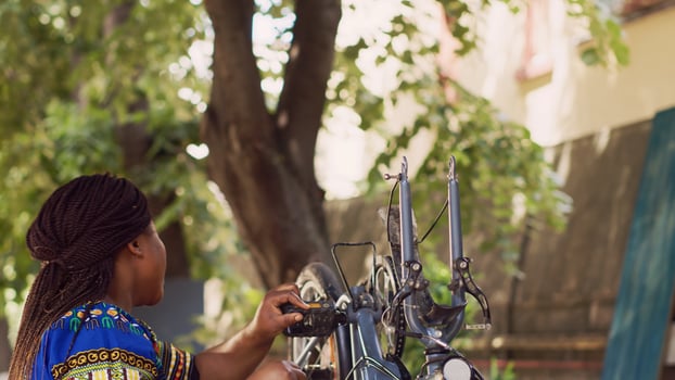 Energetic black woman detaching damaged bicycle tire for fixing and changing with new. Healthy athletic african american lady grabbing and removing bike wheel for further maintenance. photo