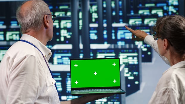 Meticulous experts looking around high tech data center, using mockup laptop to crosscheck disaster recovery plan and assess blade servers in need of replacement, preventing complications photo