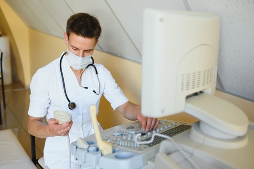 Portrait of young male technician operating ultrasound machine photo