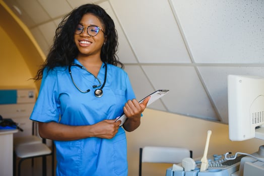 Young african-american female doctor in white coat using ultra ultrasound scanning machine and looking on the screen. African woman doctor working on modern ultrasound equipment. photo