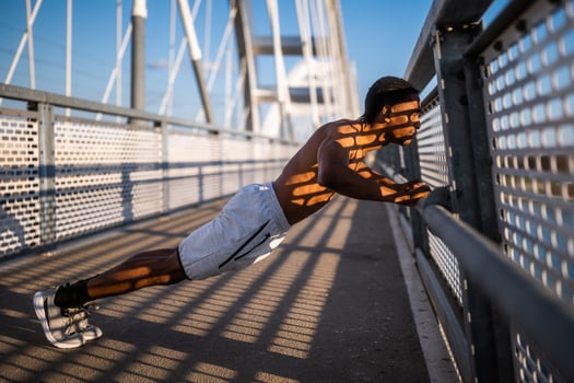 Young african-american man is exercising on the bridge in the city. He is doing push-ups. photo