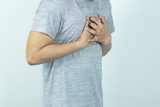 asian man pressing chest with painful expression. Severe heartache, having a heart attack or painful cramps, heart disease. photo