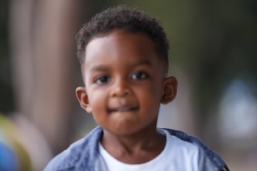 Mixed race African and Asian boy is playing at the outdoor area. smiling happy boy has fun running on the beach. portrait of boy lifestyle with a unique hairstyle. photo