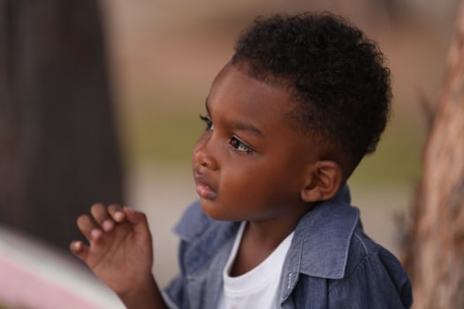 Mixed race African and Asian boy is playing at the outdoor area. smiling happy boy has fun running on the beach. portrait of boy lifestyle with a unique hairstyle. photo