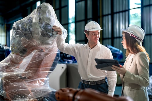 Sales manager and factory owner in suits negotiating selling robots used in the factory. Business engineers meeting and checking new machine robot. Workers walking at warehouse welding machine. photo