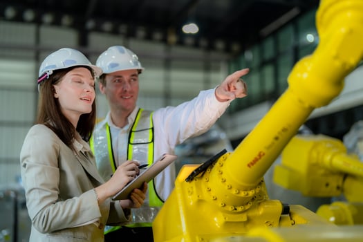 Factory engineers inspecting on machine with smart tablet. Worker works at heavy machine robot arm. The welding machine with a remote system in an industrial factory. Artificial intelligence concept. photo