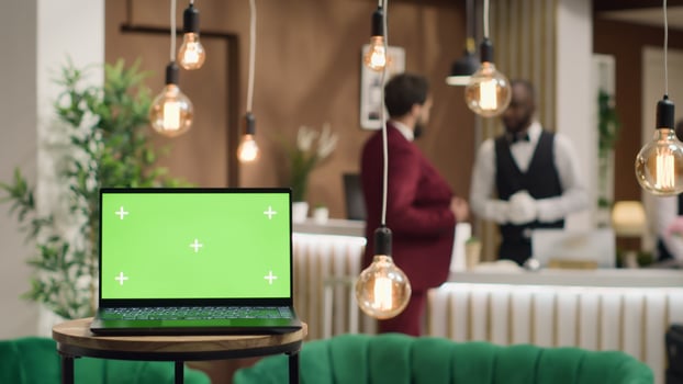 Laptop with blank greenscreen template near hotel reception front desk, people arriving in lobby travelling for work. In luxury resort, businessmen attending official conference. photo