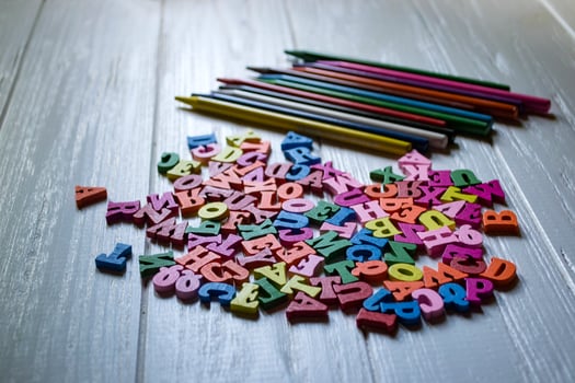 Multicolor letters and set of pencils on the table. Colorful wooden alphabet and pencils on a table. photo