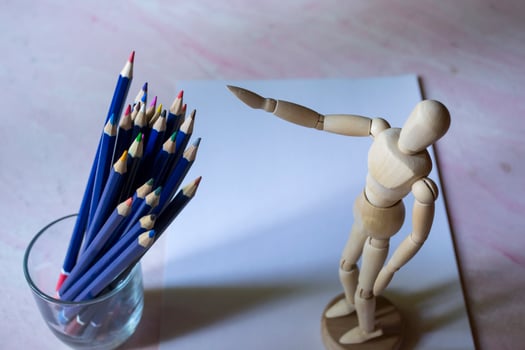 Colored pencils, empty paper and dummy for drawing on the table. photo