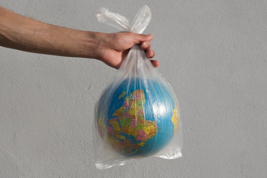Globe in a plastic bag. Concept of plastic pollution of the earth on white background. photo